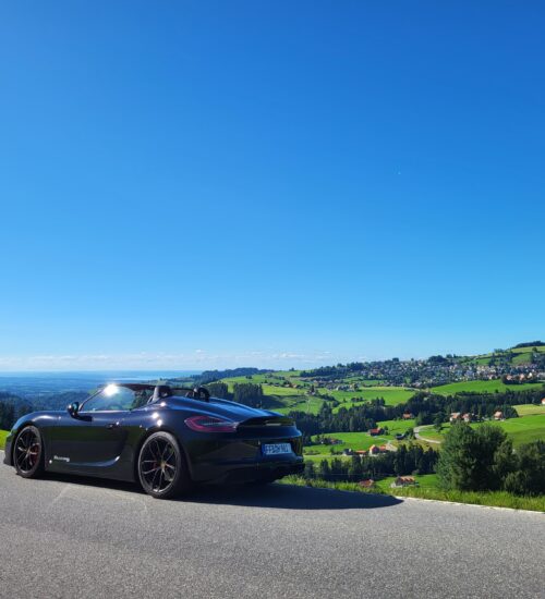 schwarzer Porsche steht auf Panoramastraße mit Ausblick auf Landschaft