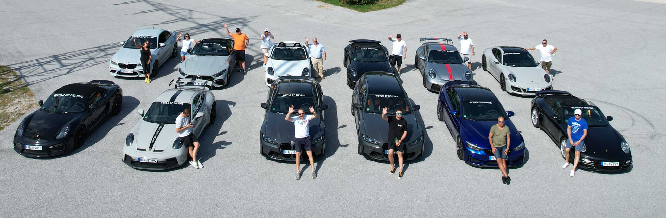 12 Autos stehen in zwei Reihen und die Fahrer stehen davor von der Tour Kurvenjagd